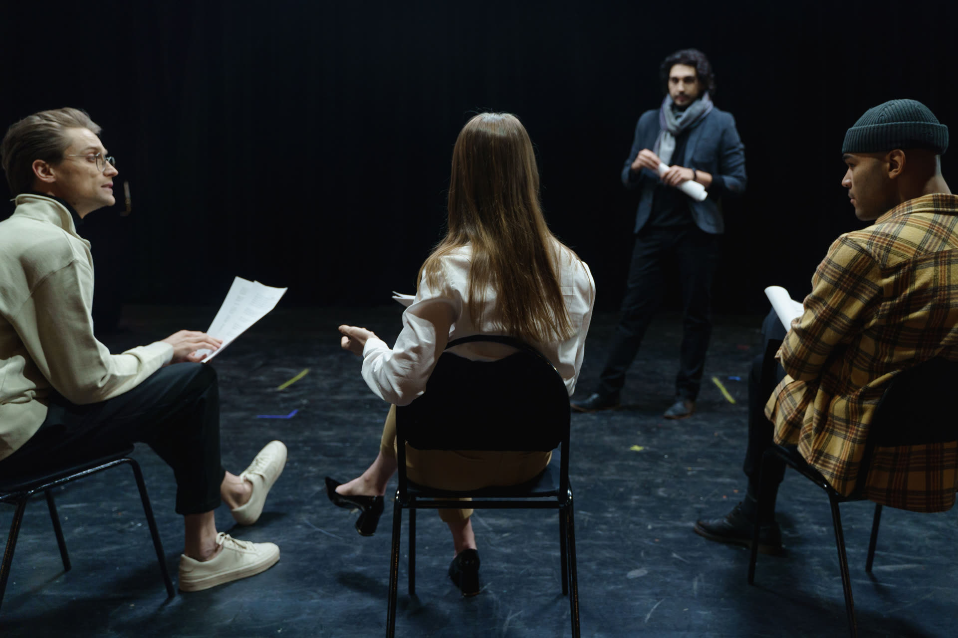 People seated in a rehearsal circle reviewing scripts