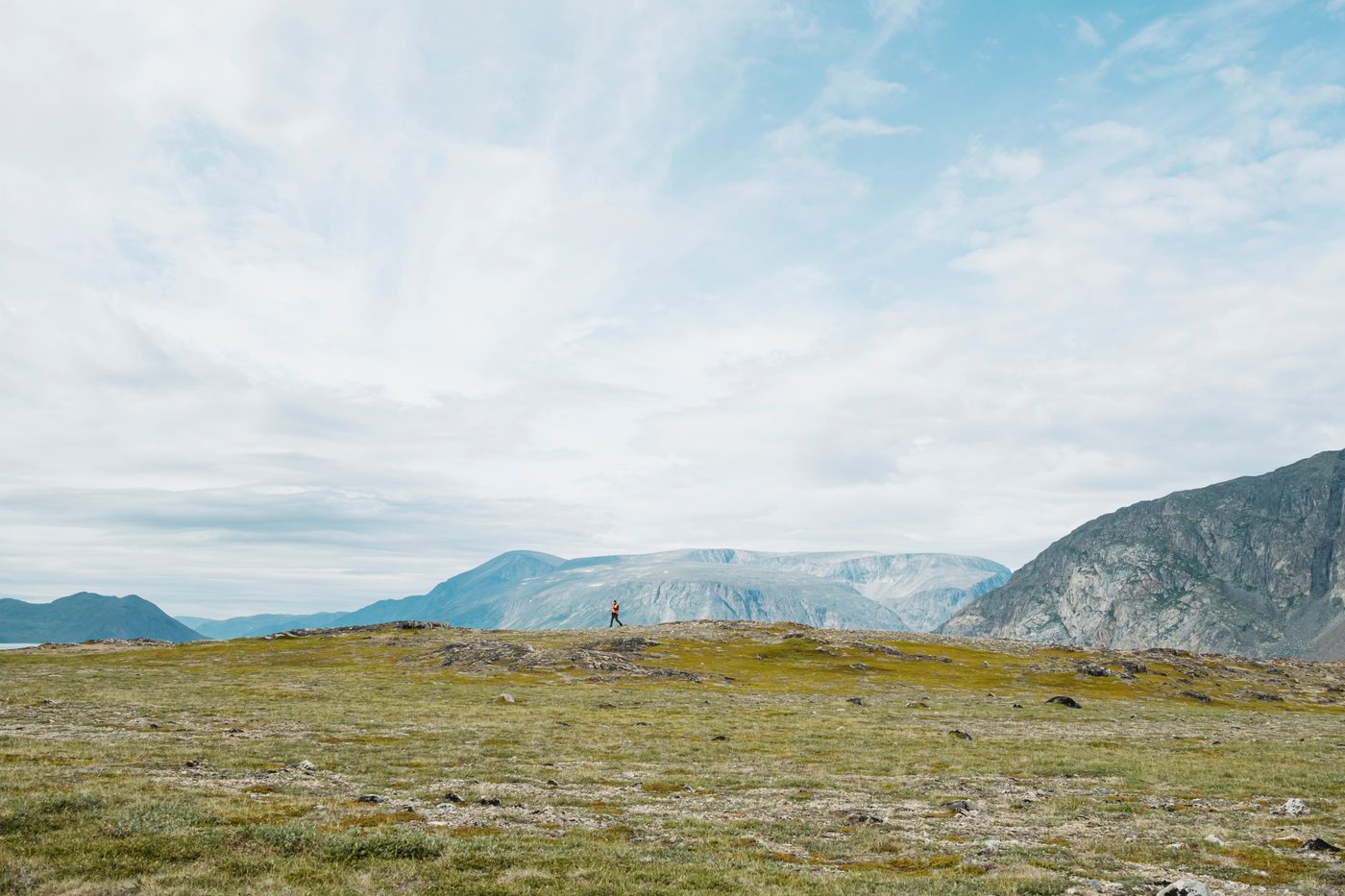 Person walking across a remote tundra landscape