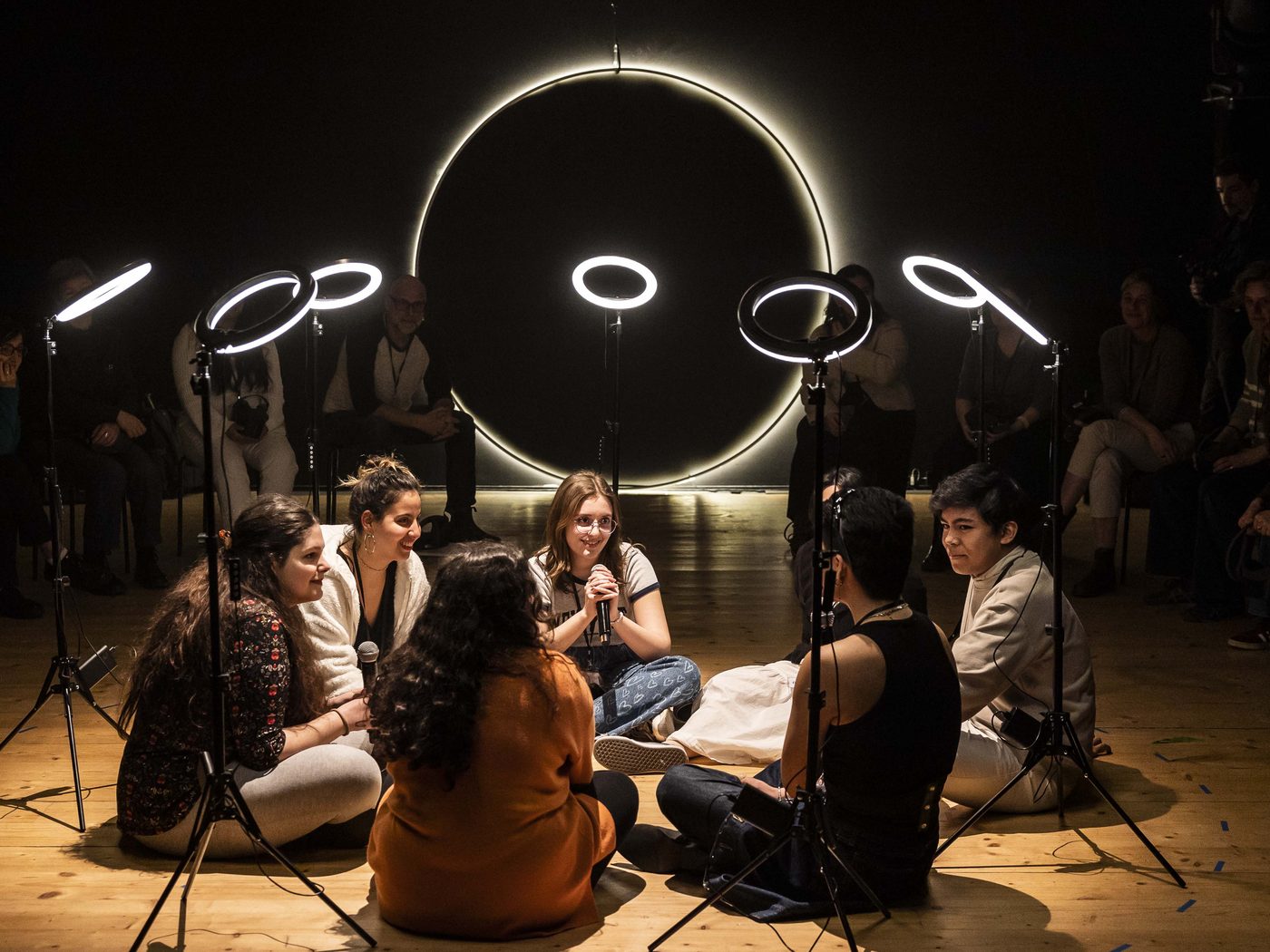 Audience gathered around a glowing circular light installation