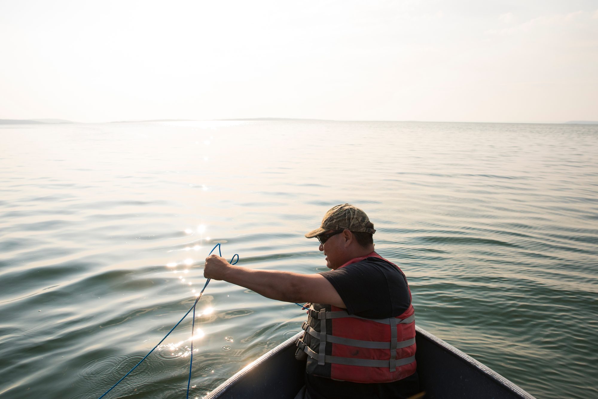 Person in a boat on a northern lake drawing a line from the water